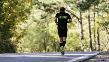 back view of sporty man runner running on mountain plateau in summer photo