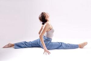 retrato de una hermosa joven con un cuerpo atlético y flexible haciendo estiramientos de piernas. aislado foto