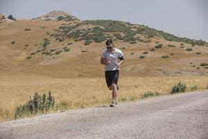 sporty man runner running on mountain plateau in summer photo