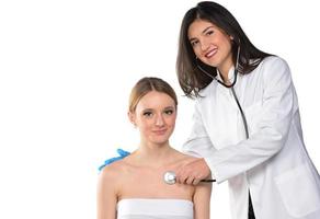 Caring young female doctor in medical facemask hold stethoscope listen to patient heart in hospital. photo