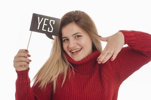 Woman holding engagement ring and sign saying YES photo