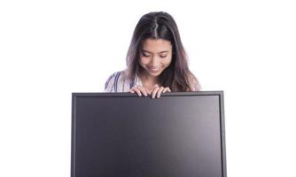 Portrait of young beautiful woman peeping at the camera holding white blank sign showing on it with finger. photo