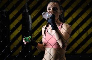 female fighter drinking water and resting after the training. photo