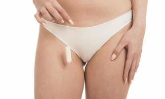 Female Period and Intimate Hygiene. Closeup cropped view of young woman in white panties holding tampon photo