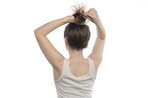 modelo femenino arreglando su cabello. mujer atando el cabello en un moño. foto