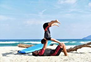 una pareja deportiva en forma practicando acro yoga con su pareja juntos. Una pareja deportiva en forma practicando yoga acrobático juntos en la playa foto