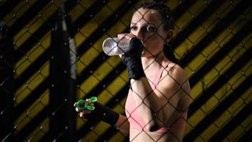 female fighter drinking water and resting after the training photo
