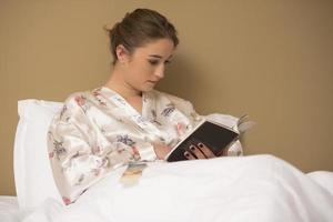 hermosa joven leyendo un libro antes de ir a dormir. foto