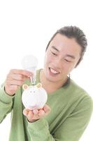 Asian man saving money in a piggy bank photo