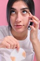 Close up beauty portrait of a young beautiful woman cleaning her face with a cotton pad photo