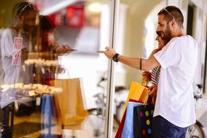 Portrait of cheerful Caucasian young couple man and woman holding many paper bags after shopping while walking and talking on street. Happy family couple with packages outdoor. Buying concept photo