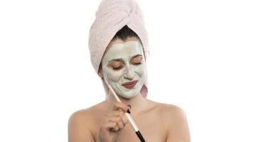 Beautiful woman having clay facial mask apply by beautician. photo