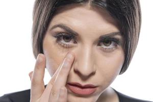 Portrait of a young woman applying liquid make up on her face. Isolated on white background photo