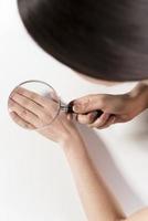 Woman looking her hand nails true magnifying glass Woman looking her hand nails true magnifying glass photo