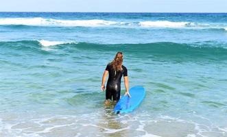 A man is standing with a surf in his hands on the sea shore. photo