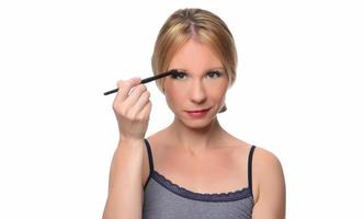 Image of joyful woman smiling at camera and using makeup brush photo