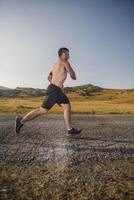 corredor de hombre deportivo corriendo en la meseta de la montaña en verano foto