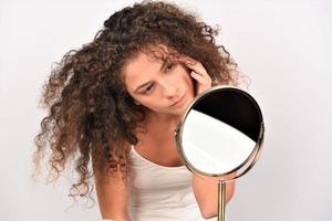 woman looking in mirror check face after mask cream beauty treatment feels satisfied photo