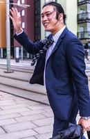 Handsome Asian businessman wearing suit and walking outdoors, successful manager during break walking in the city. photo