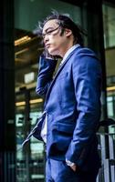 Handsome Asian businessman wearing suit and walking outdoors, successful manager during break walking in the city. photo