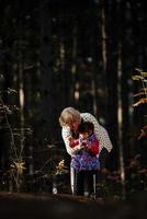 Grandmother and her autistic grand daughter enjoying holiday together outdoors, lying on green grass on blanket and smiling to camera. Leisure family lifestyle, happiness and moments. photo