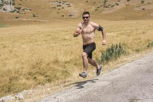 corredor de hombre deportivo corriendo en la meseta de la montaña en verano foto