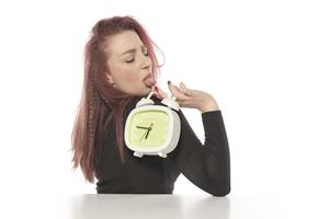 worried young woman holding alarm clock in her hand photo