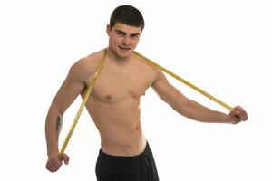 modelo masculino con gran cuerpo midiendo su cuerpo con cinta métrica foto