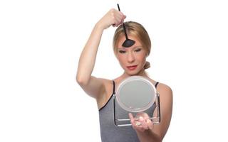 Image of joyful woman smiling at camera and using makeup brush photo