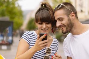 un par de turistas divirtiéndose caminando por las calles de la ciudad en vacaciones - amigos felices riéndose juntos en vacaciones - concepto de personas y vacaciones foto