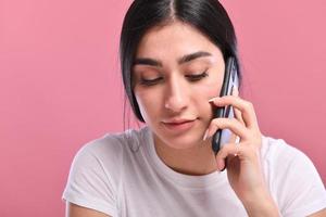 Portrait of a smiling young casual brunette woman talking on mobile phone photo