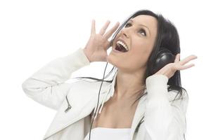 bella chica moderna cantando su canción favorita, escuchando música con auriculares inalámbricos, sonriendo y bailando foto