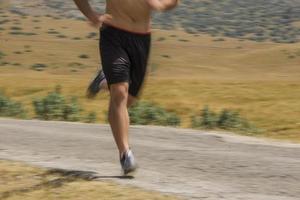 corredor de hombre deportivo corriendo en la meseta de la montaña en verano foto