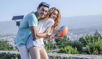 pareja jugando fútbol americano en un caluroso día de verano. sesión de fotos de pareja jugando al rugby