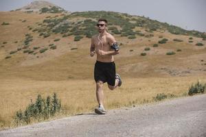 corredor de hombre deportivo corriendo en la meseta de la montaña en verano foto