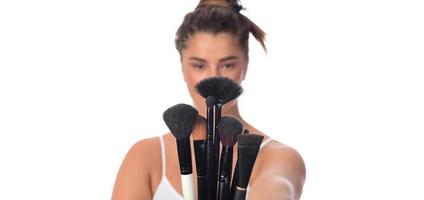 young girl posing with makeup brushes on a white background photo