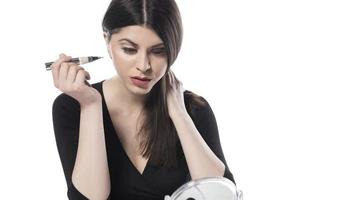 Portrait of a young woman applying liquid make up on her face. Isolated on white background photo