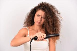 nice-looking attractive mad irritated wavy-haired girl ironing straightening messy curls keratin therapy treatment photo