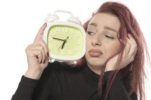 worried young woman holding alarm clock in her hand photo