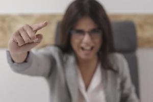 Portrait of aggresive boss scolding and shouting at employees threatening with a finger photo