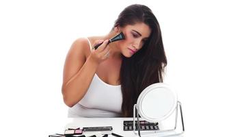 Portrait of a young woman applying make up on her face. Isolated on white background photo