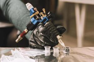 close up tattoo machine. Woman creating picture on hand with it in salon photo