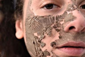Beautiful woman removing clay facial mask from her face photo
