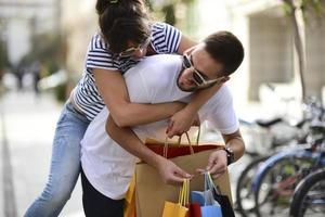 Portrait of cheerful Caucasian young couple man and woman holding many paper bags after shopping while walking and talking on street. Happy family couple with packages outdoor. Buying concept photo