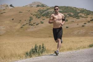 corredor de hombre deportivo corriendo en la meseta de la montaña en verano foto