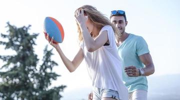 pareja jugando fútbol americano en un caluroso día de verano. sesión de fotos de pareja jugando al rugby