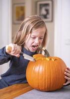 beautiful blond boy carving pumpkin with knife for Halloween. Halloween concept photo