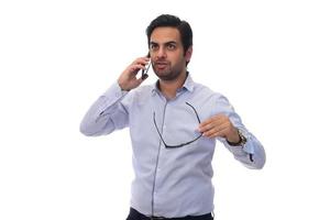 hombre de negocios árabe hablando por su teléfono celular y sosteniendo papeleo en el portapapeles. aislado en blanco foto