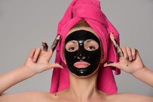 beautiful female model with black facial cosmetic mask. Isolated on gray background photo