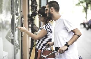 Portrait of cheerful Caucasian young couple man and woman holding many paper bags after shopping while walking and talking on street. Happy family couple with packages outdoor. Buying concept photo